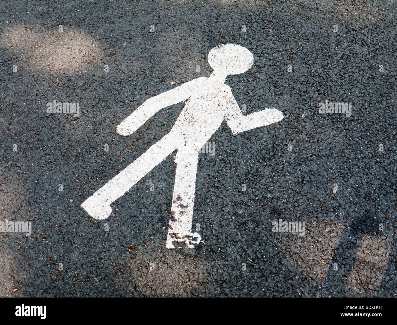 Un pittogramma su asfalto di una strada simboleggia un pedone. Foto Stock