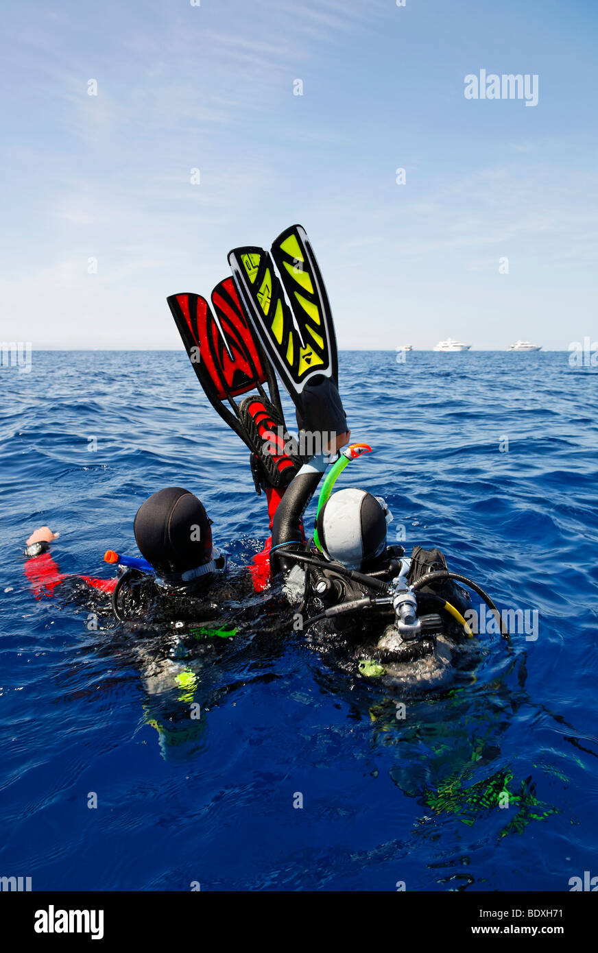 Il drifting subacquei in mare stanno tentando di ottenere l'attenzione di persone su navi di immersioni all'orizzonte agitando con le loro pinne per nuoto Foto Stock