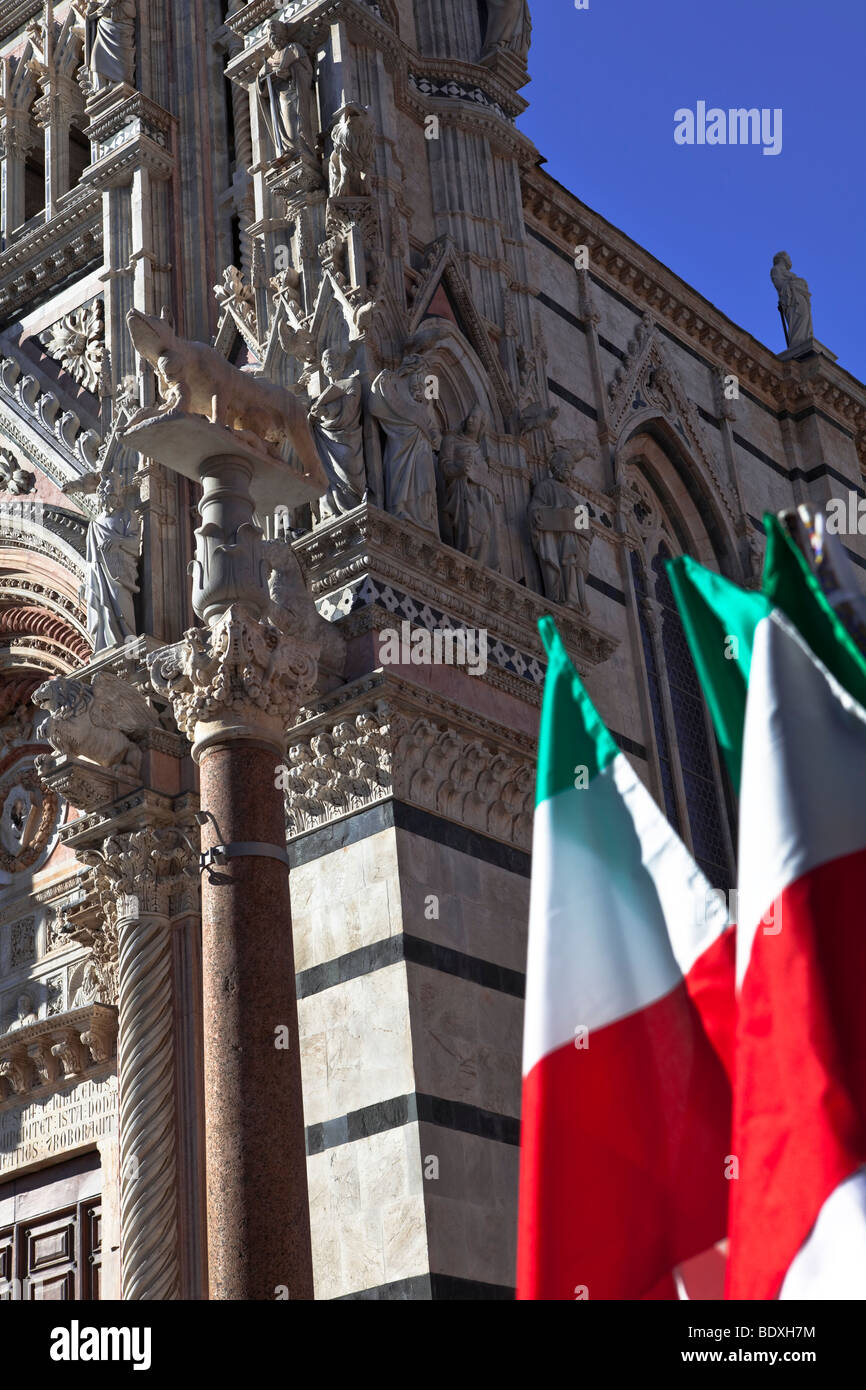 Le strisce di marmo torre campanaria del Duomo e bandiera italiana da Piazza del Duomo a Siena, Toscana, Italia. Foto Stock