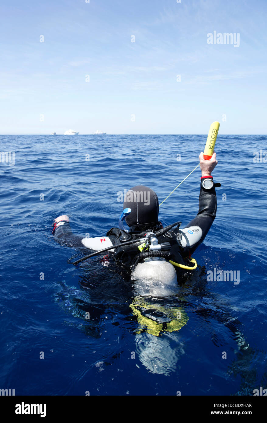 Il drifting subacqueo in mare tenendo un trasmettitore di Enos, un sistema elettronico di allarme di emergenza e sistema di posizionamento al di sopra del livello dell' acqua, così Foto Stock