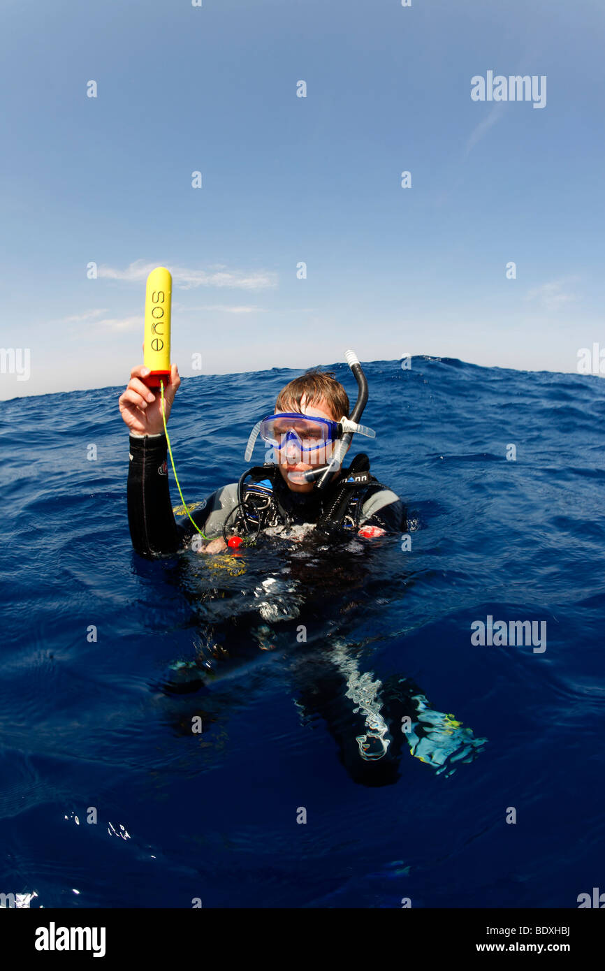 Il drifting subacqueo in mare tenendo un trasmettitore di Enos, un sistema elettronico di allarme di emergenza e sistema di posizionamento al di sopra del livello dell' acqua, così Foto Stock