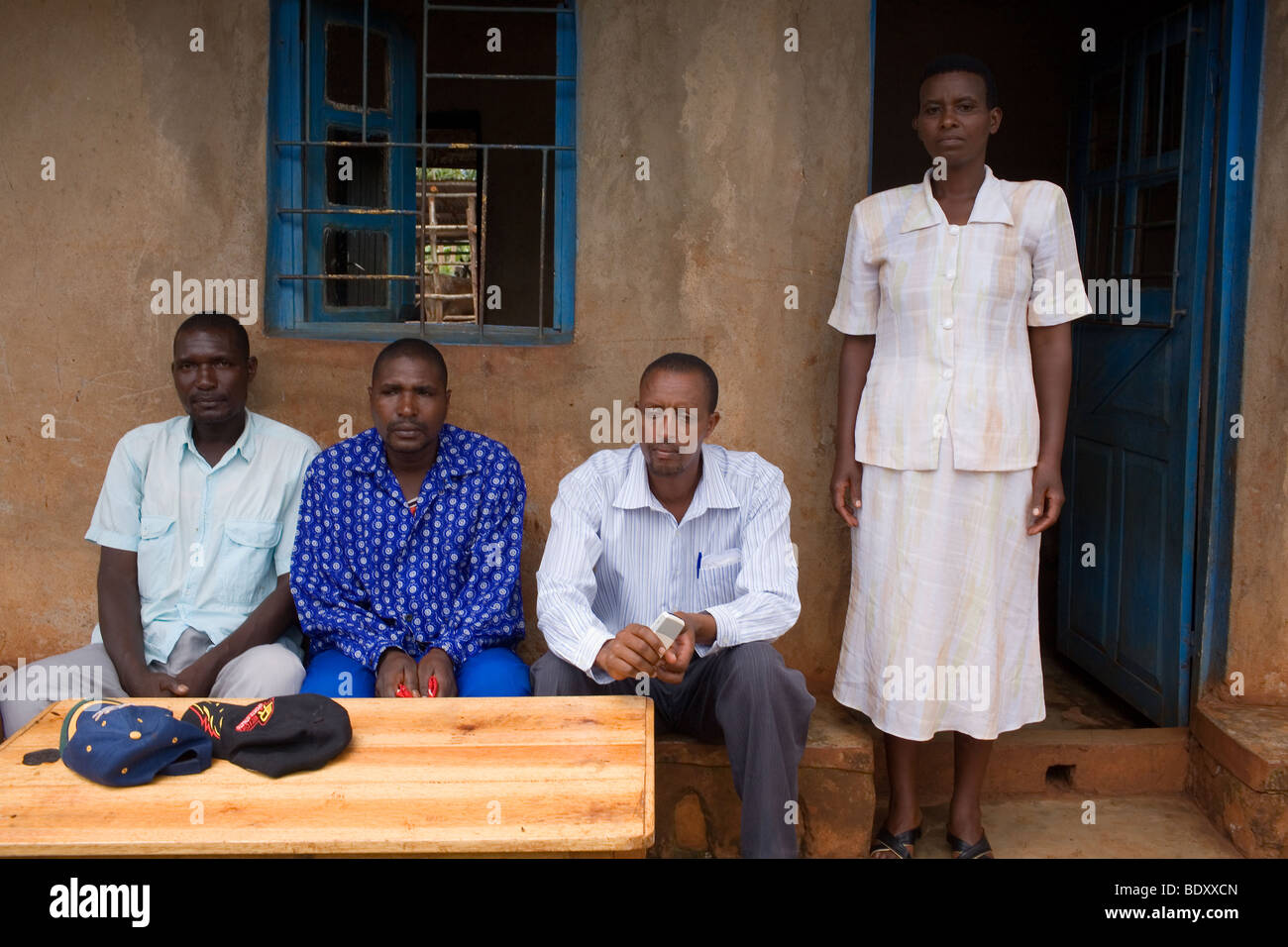 Due uomini Hutu (sinistra) sedersi con un tutsi fratello e sorella al di fuori di una casa in un villaggio ruandese. Foto Stock