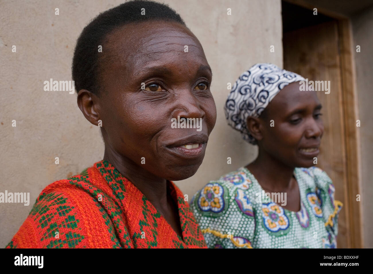 Una donna hutu e tutsi, donne che sono amici di stand al di fuori di una casa finanziato dal raggiungere il Ruanda di carità. Foto Stock