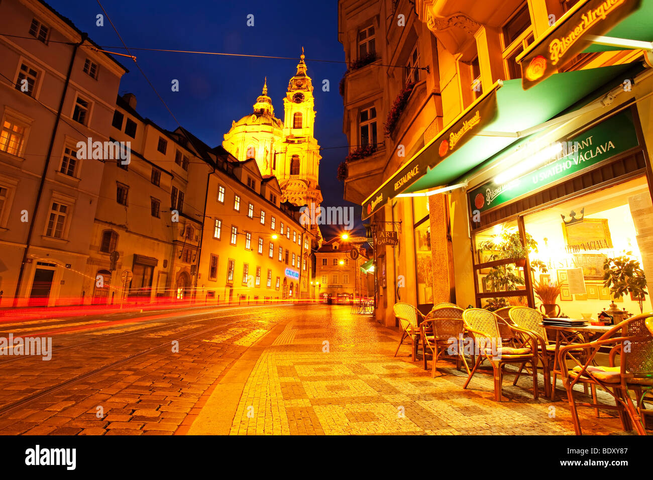 Repubblica Ceca, Praga, Cattedrale di San Nicola. Notte estiva a Praga, una strada acciottolata nella Città piccola, con alcune tracce di coda da auto di passaggio Foto Stock