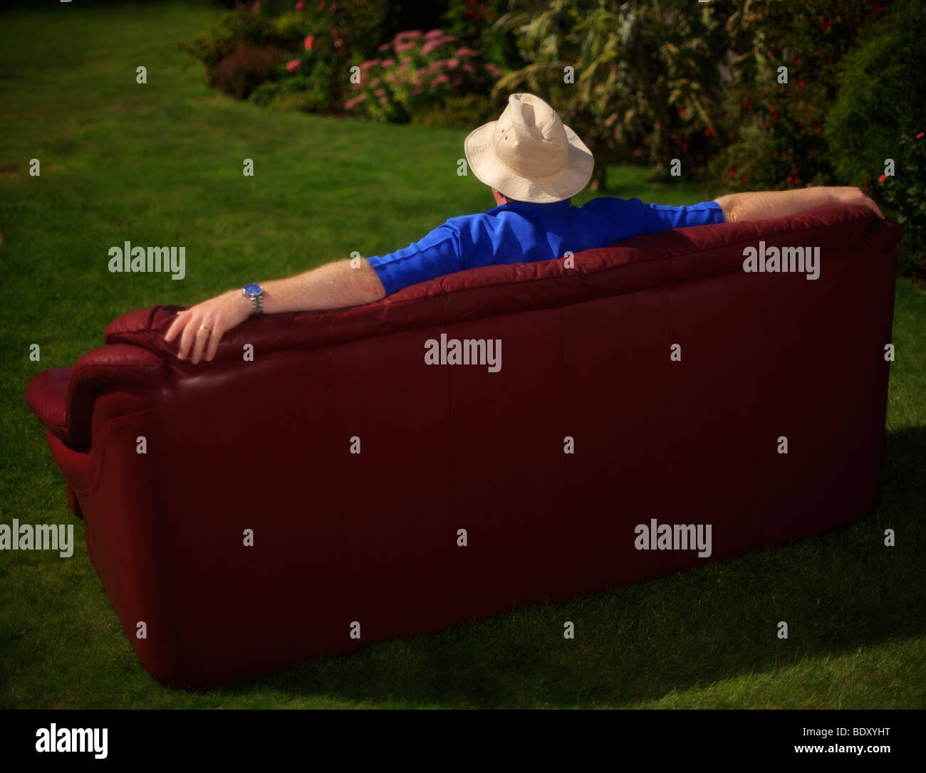 Uomo seduto in giardino su un divano. Foto Stock