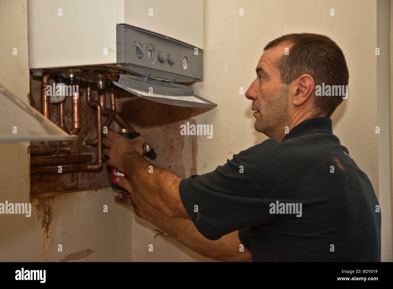 British Gas fitter sostituisce una vecchia caldaia inefficiente con una nuova energia efficiente condensatore caldaia. Foto Stock