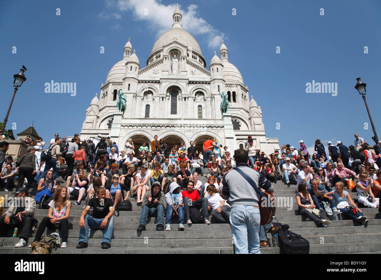 I turisti di ascoltare un animatore di strada su i passi prima di Sacre Coeur, Parigi, Francia Foto Stock