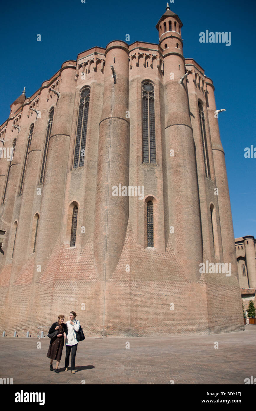 Due donne passeggiata dall'estremità orientale di albi di imponenti costruiti in mattoni Sainte-Cecile Cattedrale; il campanile è ancora più elevata Foto Stock