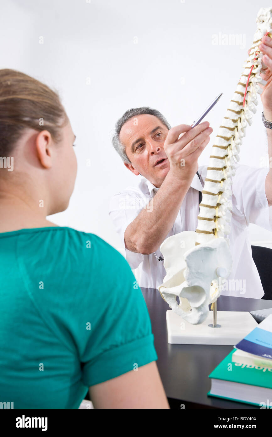 Medico spiegare una colonna vertebrale di un paziente giovane Foto Stock
