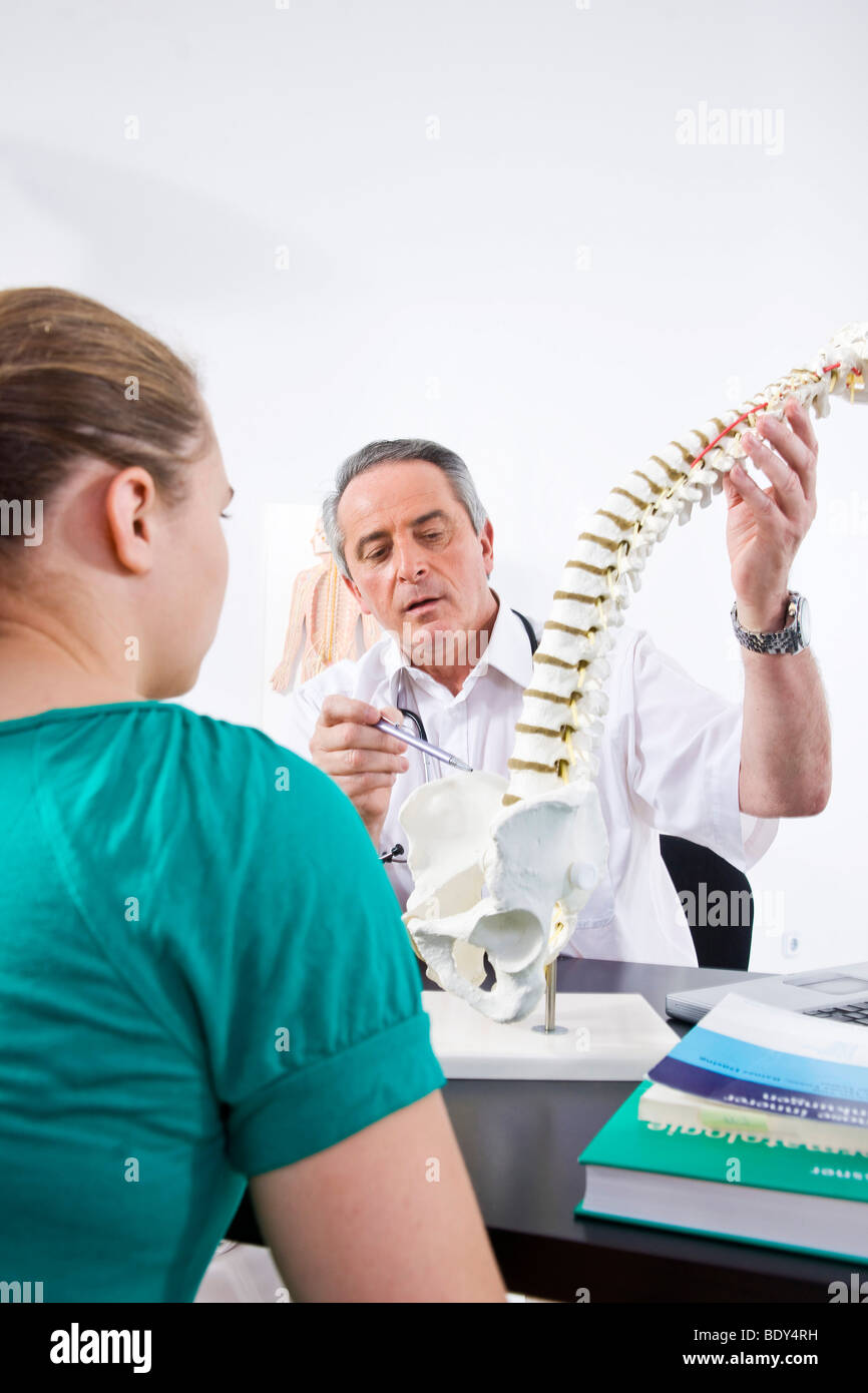 Medico spiegare una colonna vertebrale di un paziente giovane Foto Stock