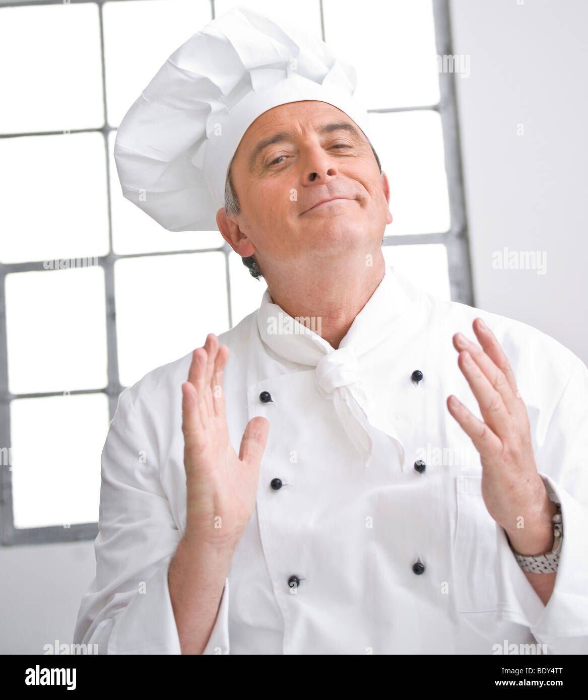 Lo Chef indossando un chef hat esprimendo la sua soddisfazione Foto Stock