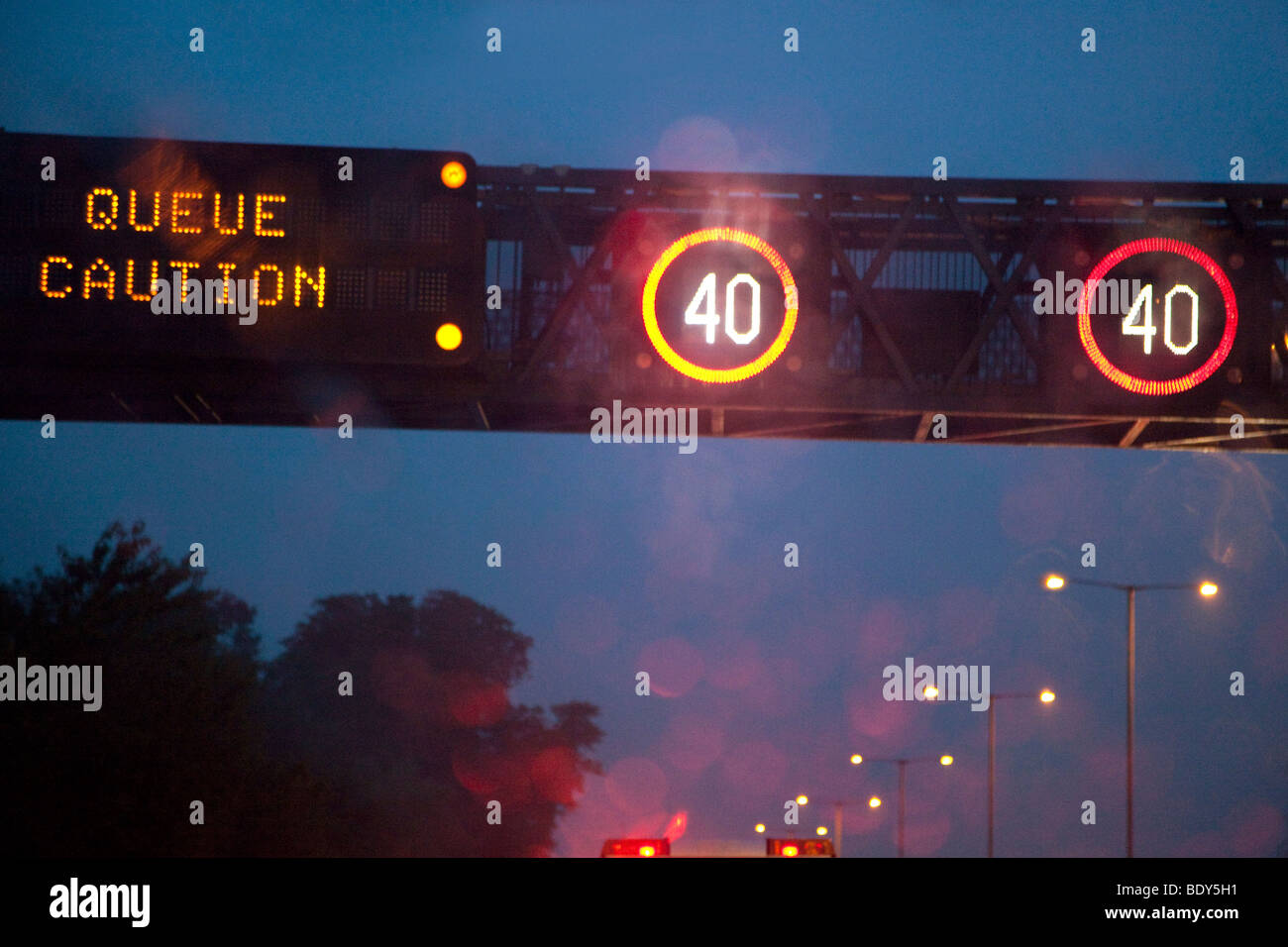Velocità ridotta luci sul tettuccio di gantry su autostrada per informare i conducenti di accodamento di traffico, Inghilterra. Foto Stock