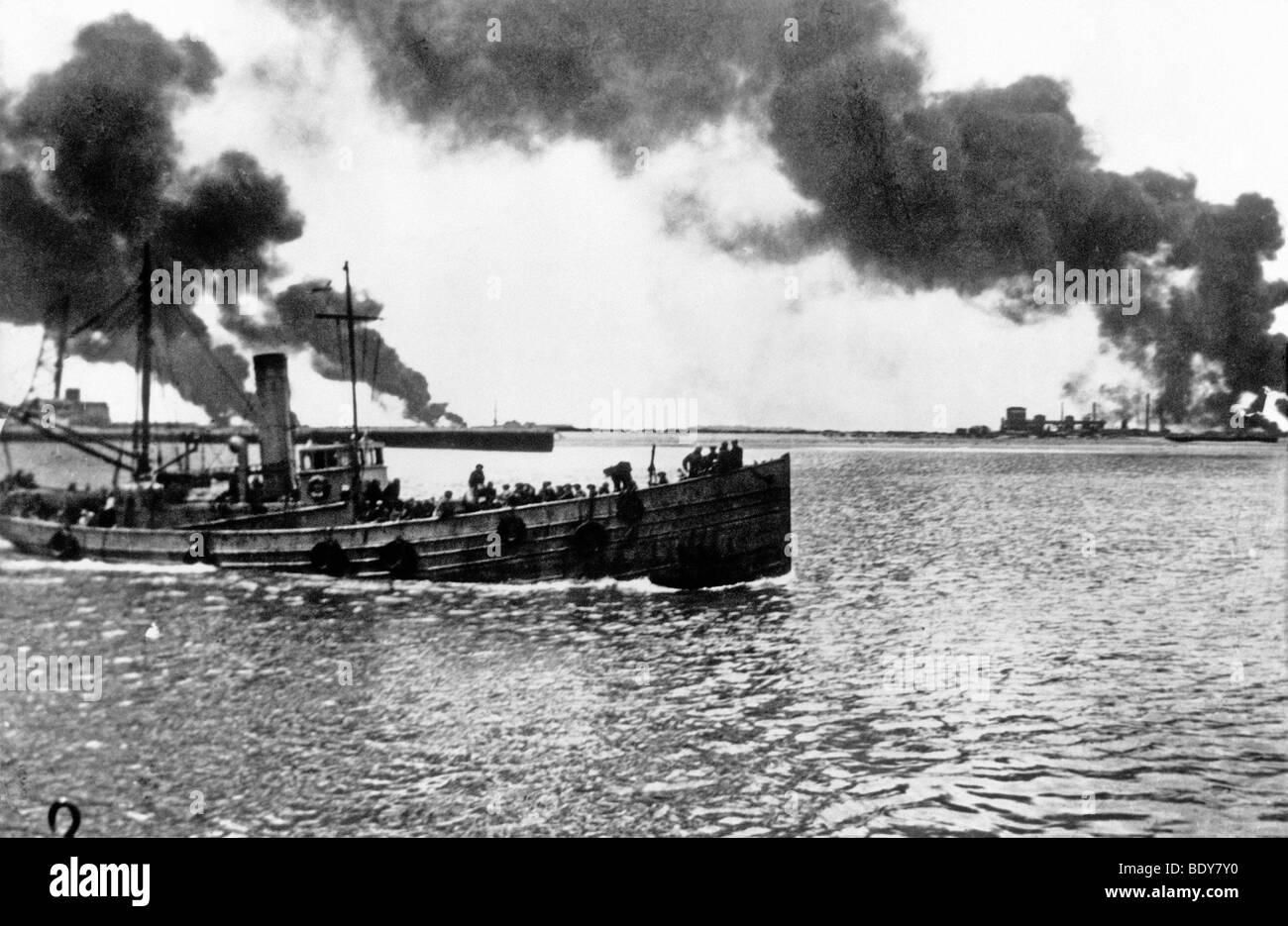 DUNKIRK Salvataggio di navi traghetto truppe dalla mole a Dunkerque nel giugno 1940 come un olio impianto di magazzinaggio brucia in distanza Foto Stock