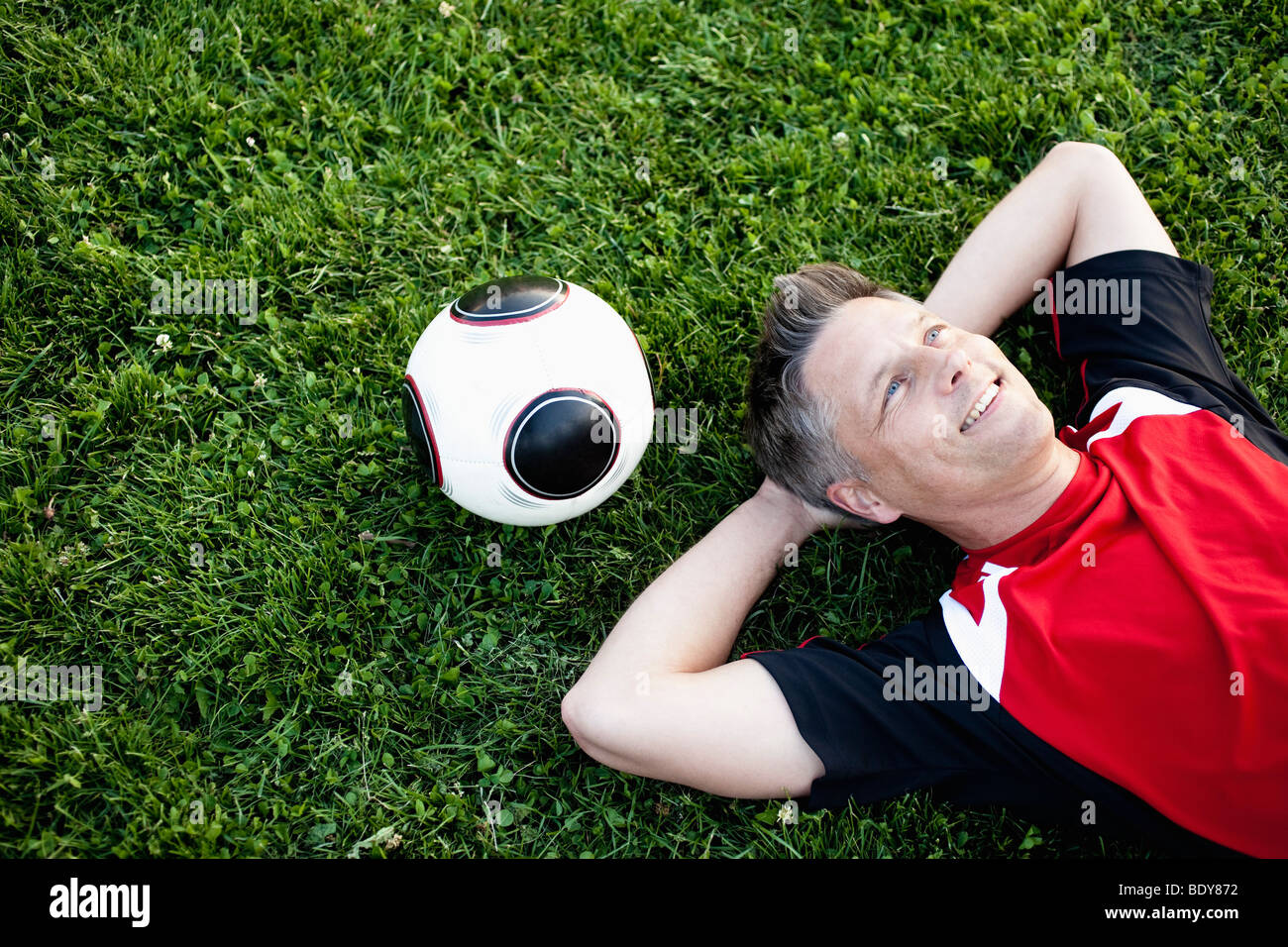Giocatore di calcio rilassante sull'erba Foto Stock
