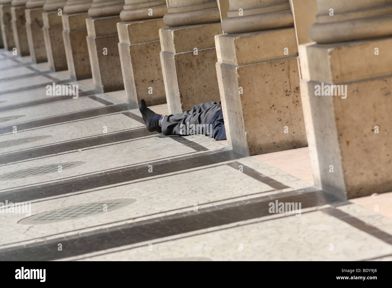 La persona senza dimora che giace tra le colonne, Palais Royale, Parigi, Francia, Europa Foto Stock