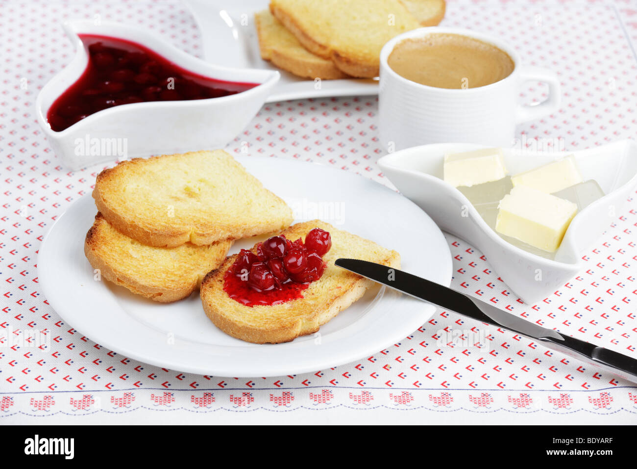 La prima colazione con pane tostato, marmellata di amarene, burro e caffè Foto Stock