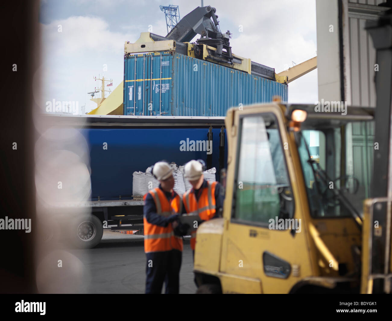 I lavoratori portuali con contenitore di spedizione Foto Stock