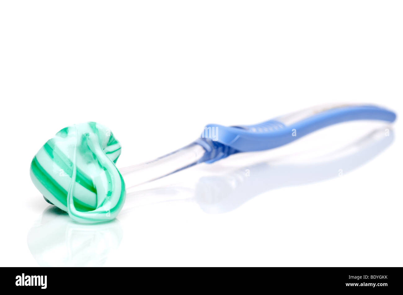 Orizzontale poco profonda attenzione uno spazzolino da denti con dentifricio in eccesso su una superficie bianca Foto Stock