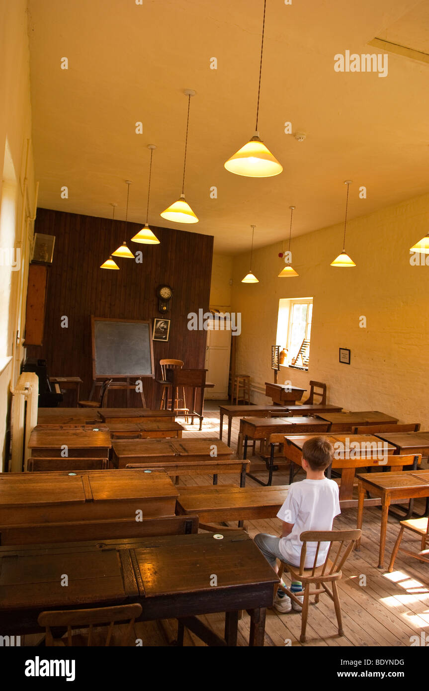 L'aula scolastica al Museo Gressenhall della vita rurale in North Norfolk Regno Unito con un piccolo ragazzo seduto sul retro Foto Stock