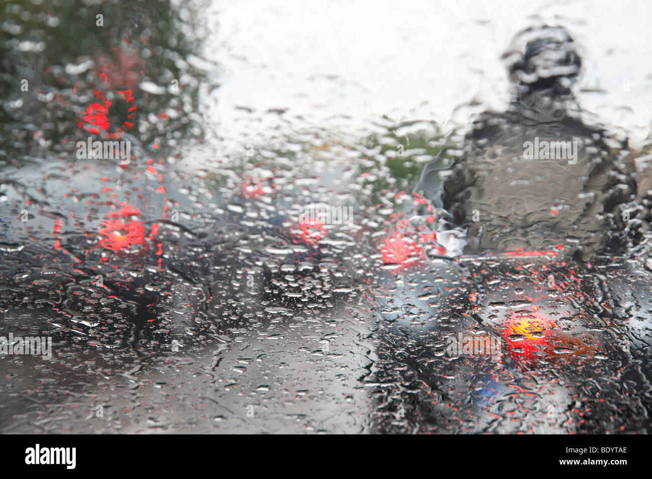 Biker è coinvolta in un ingorgo stradale; la scarsa visibilità causata dalla pioggia pesante Foto Stock