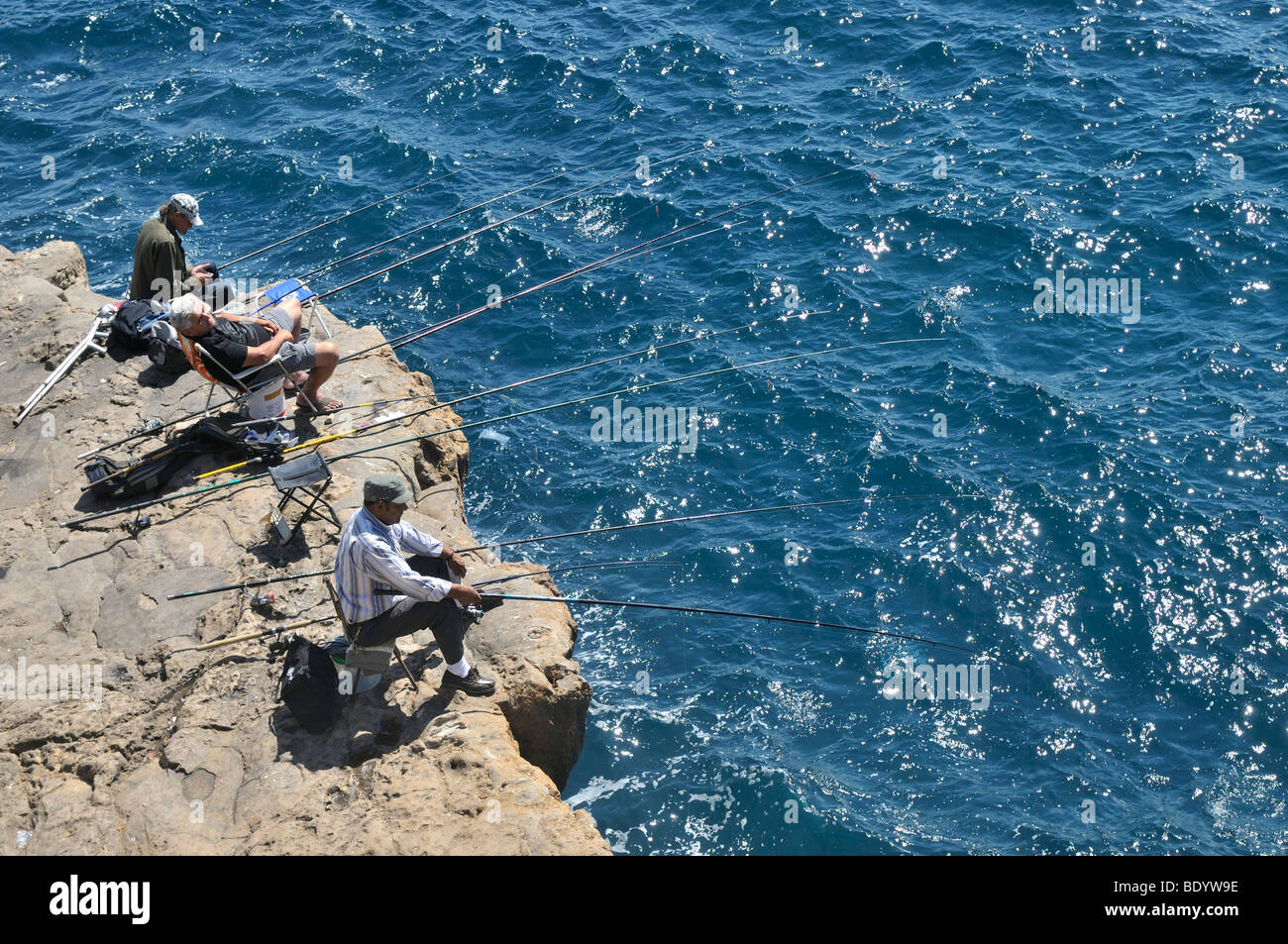 Tre pescatori su una costa rocciosa, Cascais vicino a Lisbona, Portogallo, Europa Foto Stock