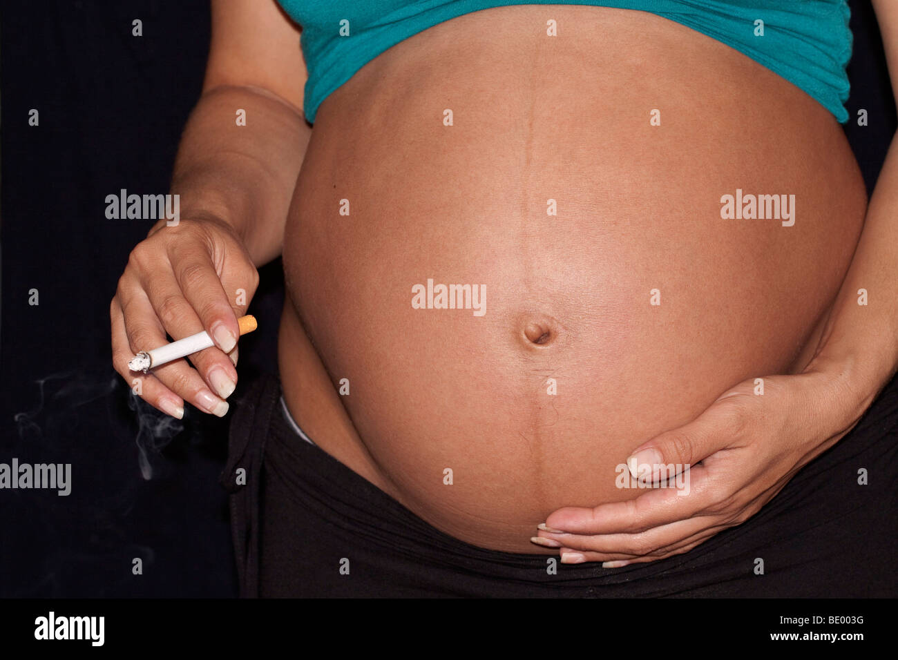 Donna incinta di fumare una sigaretta con filtro Foto Stock