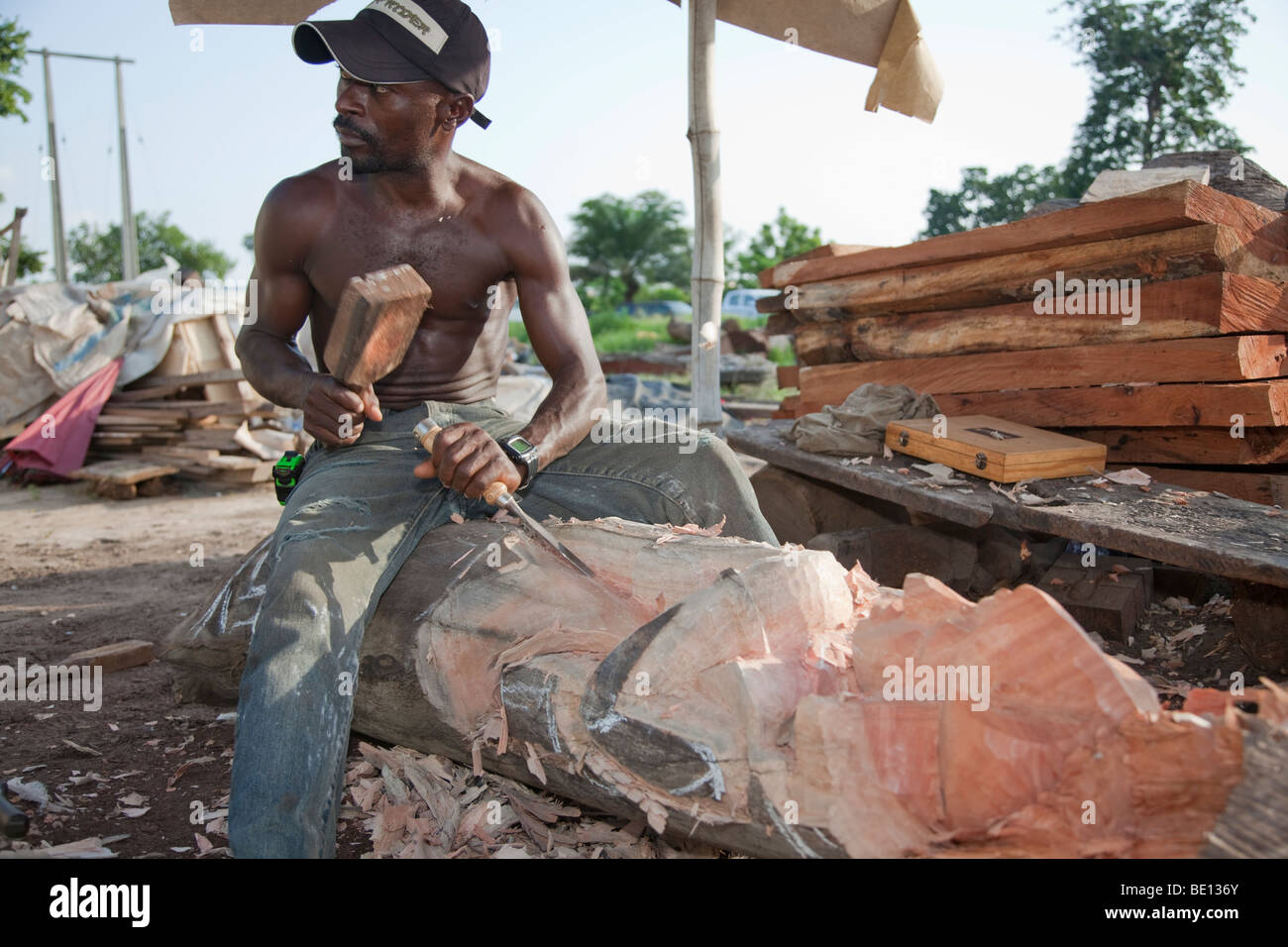 Un uomo fa sculture in legno in Nigeria la città capitale di Abuja. Foto Stock