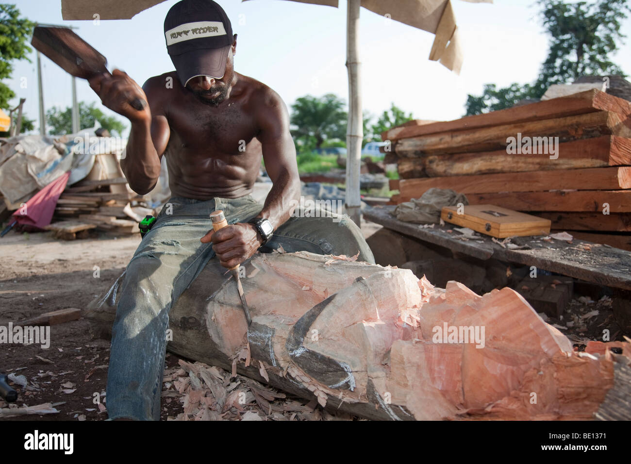 Un uomo fa sculture in legno in Nigeria la città capitale di Abuja. Foto Stock