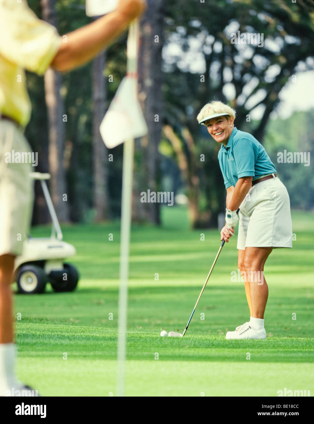 Senior golfer donna mettendo su verde Foto Stock