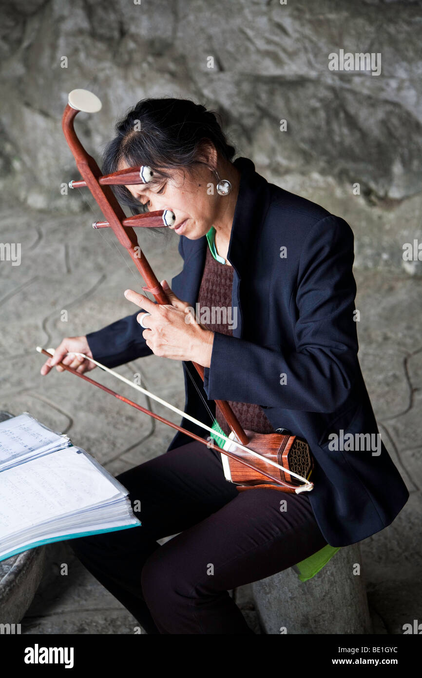 Donna in Guangsho giocando il tradizionale strumento di prua Erhu, il violino cinese Foto Stock