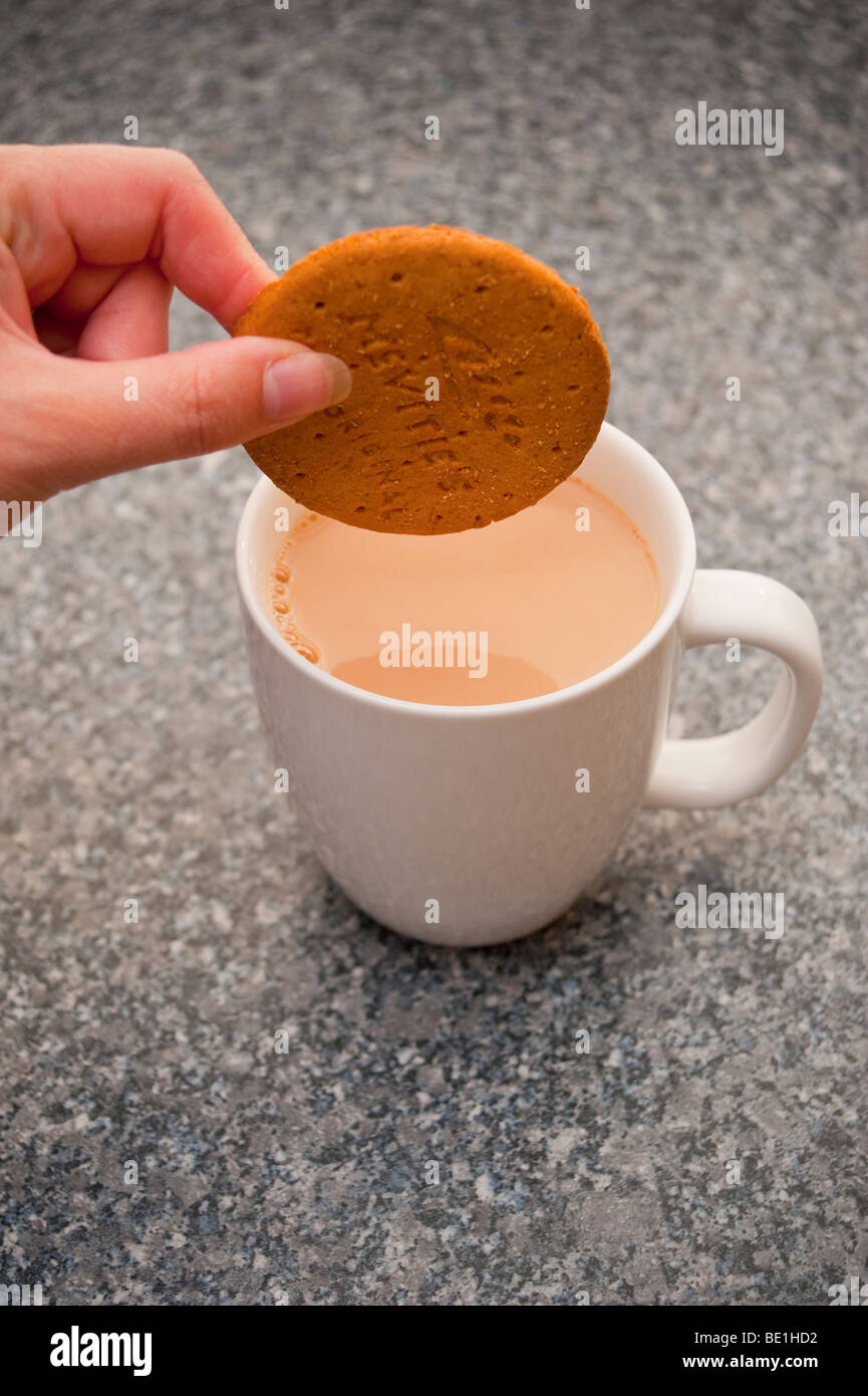 Una chiusura di una persona dunking un digestivo mcvities biscotto in una tazza di tè Foto Stock