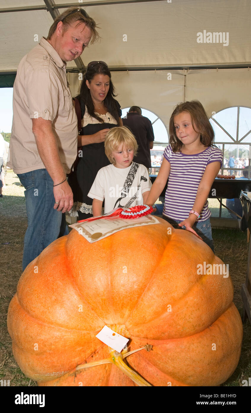 Famiglia stupita dalle dimensioni del Pumpkin vincitore nel concorso orticoltura all'Henley Show, Hambledon, Oxfordshire, Inghilterra, Regno Unito Foto Stock