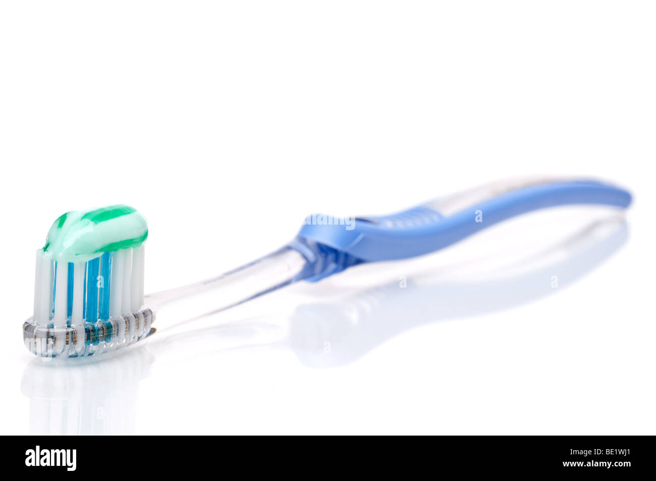 Orizzontale poco profonda attenzione uno spazzolino da denti con dentifricio su una superficie bianca Foto Stock