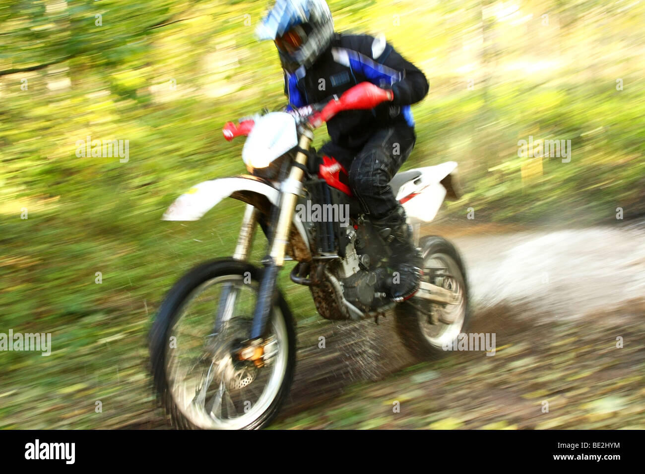 Off-road moto Varcando il fiume, spruzzi d'acqua intorno a. Immagine dinamica con motion blur. Foto Stock