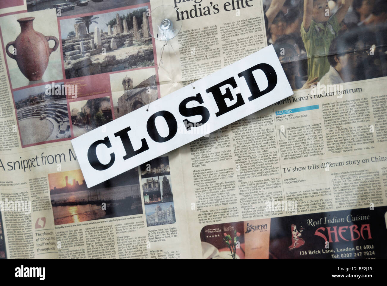 Segno chiuso e giornale in vetrina Foto Stock