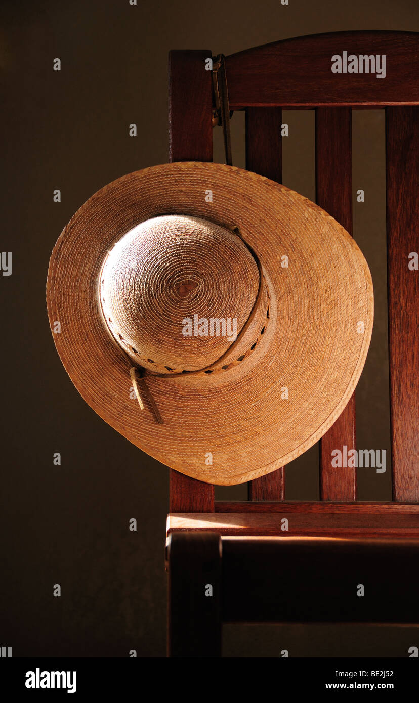 Cappello di paglia e sedia. Foto Stock