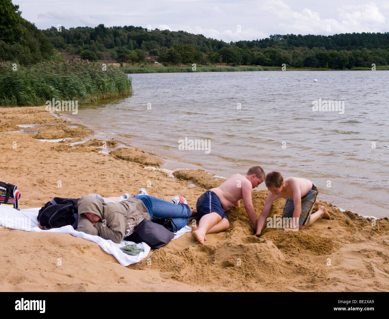 Ragazzi giocare sulla spiaggia con acqua a Frensham Great Pond. Churt, vicino a Farnham, Surrey. Regno Unito. Foto Stock