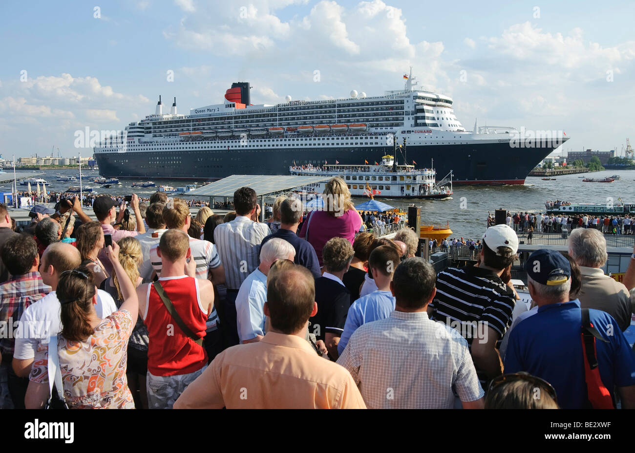 Gli spettatori a guardare la partenza della nave da crociera Queen Mary 2 dal Landungsbruecken, Ponti di Sbarco del porto di ha Foto Stock