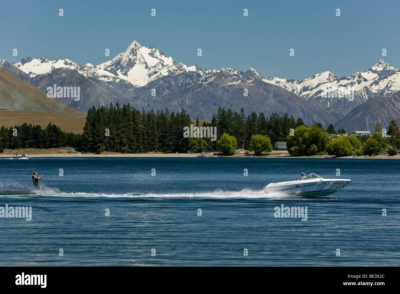 Waterskier dietro un motoscafo sul Lago di Camp con vedute delle montagne di torbida gamma di picco, Isola del Sud, Nuova Zelanda Foto Stock