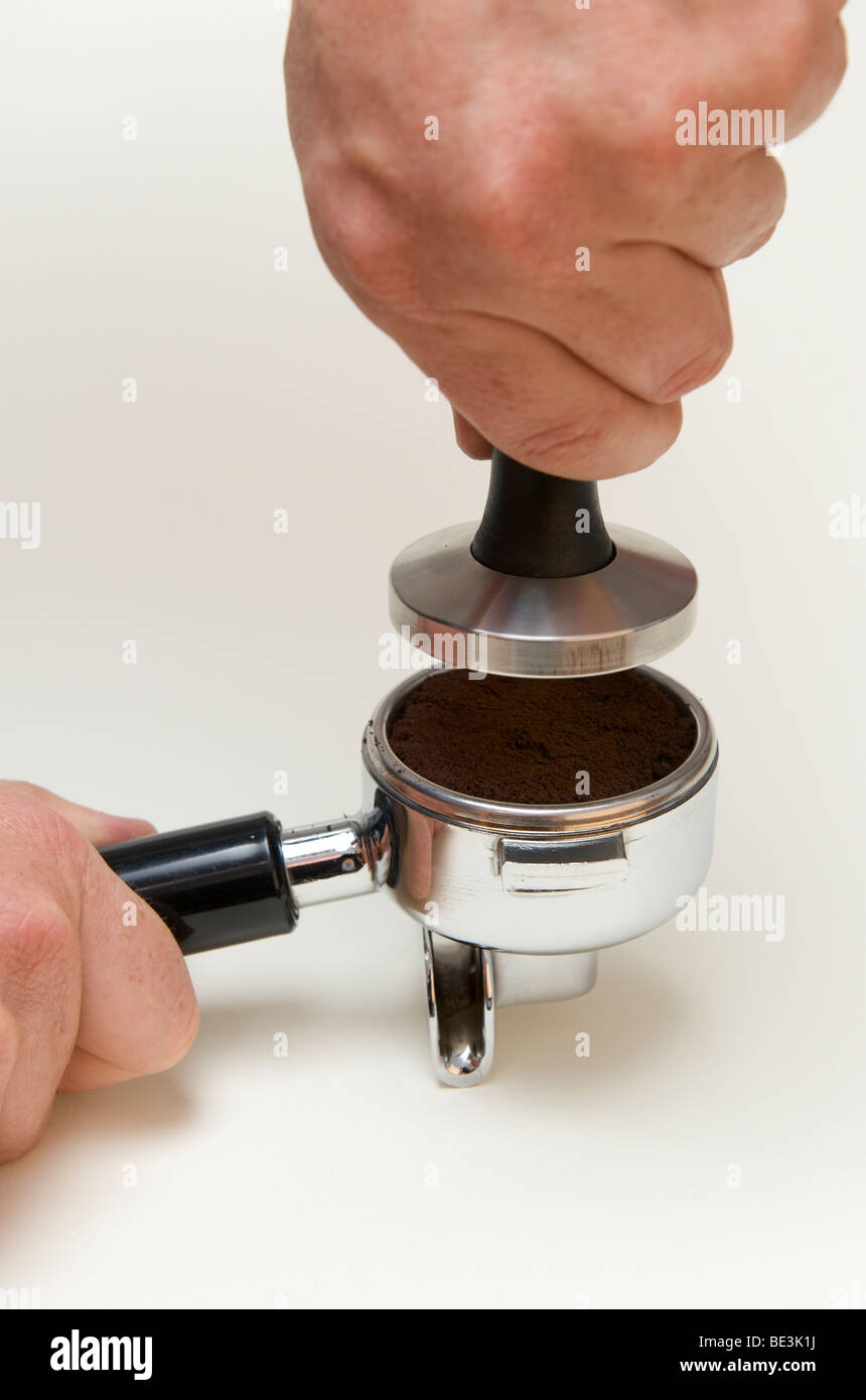 La preparazione professionale di espresso con una macchina espresso: il dispositivo antimanomissione è accuratamente impostato sul caffè macinato Foto Stock