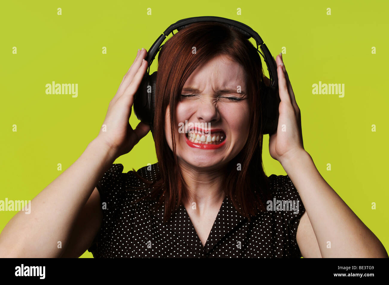 Giovane donna con le cuffie per ascoltare la musica ad alto volume con uno  sfondo verde Foto stock - Alamy