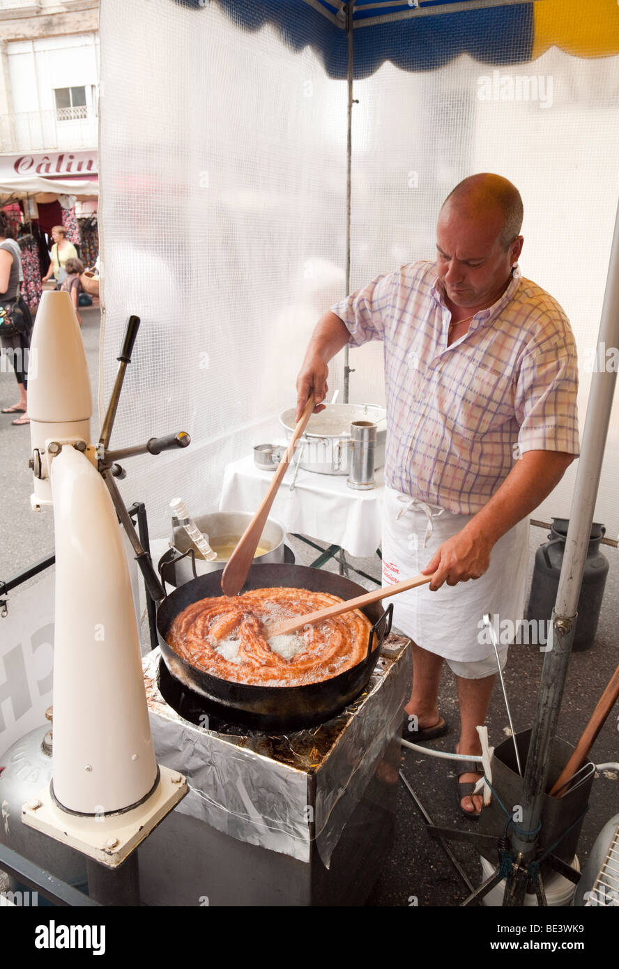Un baker rendendo le ciambelle (chichi) nel mercato, NERAC, Aquitaine, Francia Foto Stock