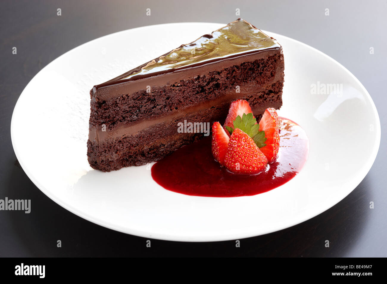 Ricca torta al cioccolato con coulis di fragola Foto Stock