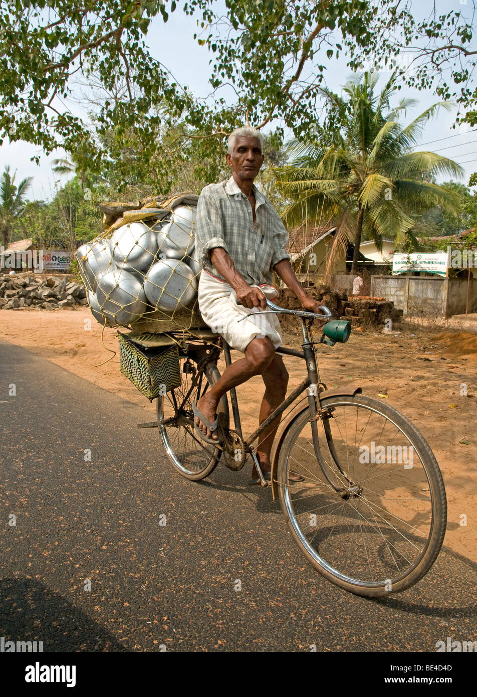 Uomo che porta la sua merce al mercato sulla sua bicicletta nelle backwaters , Kerala, India Foto Stock