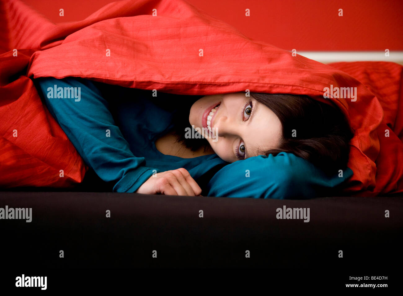 Giovane donna sotto coperta di rosso Foto Stock