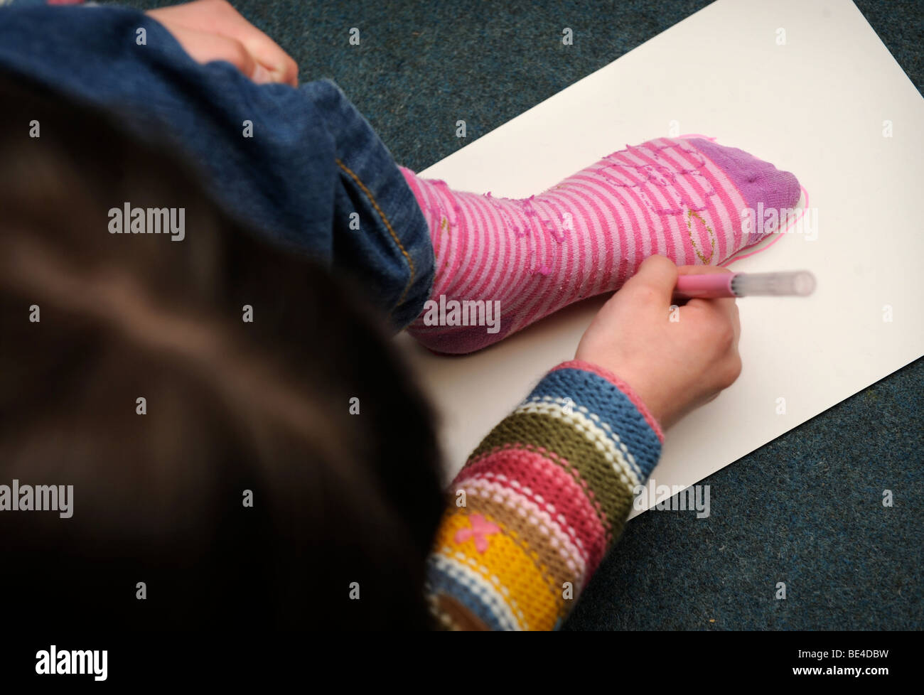 Una giovane ragazza traccia il profilo del suo piede ad una scuola domenicale di Regno Unito Foto Stock
