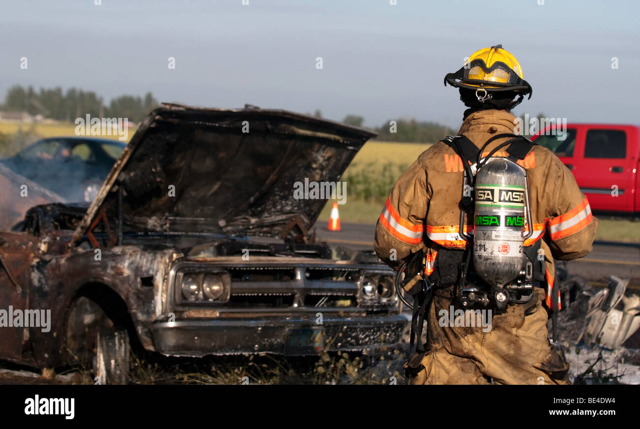 'Un pompiere ispeziona i postumi di una superstrada macchina fuoco.' '( B / W Image = Alamy essere5091)" Foto Stock
