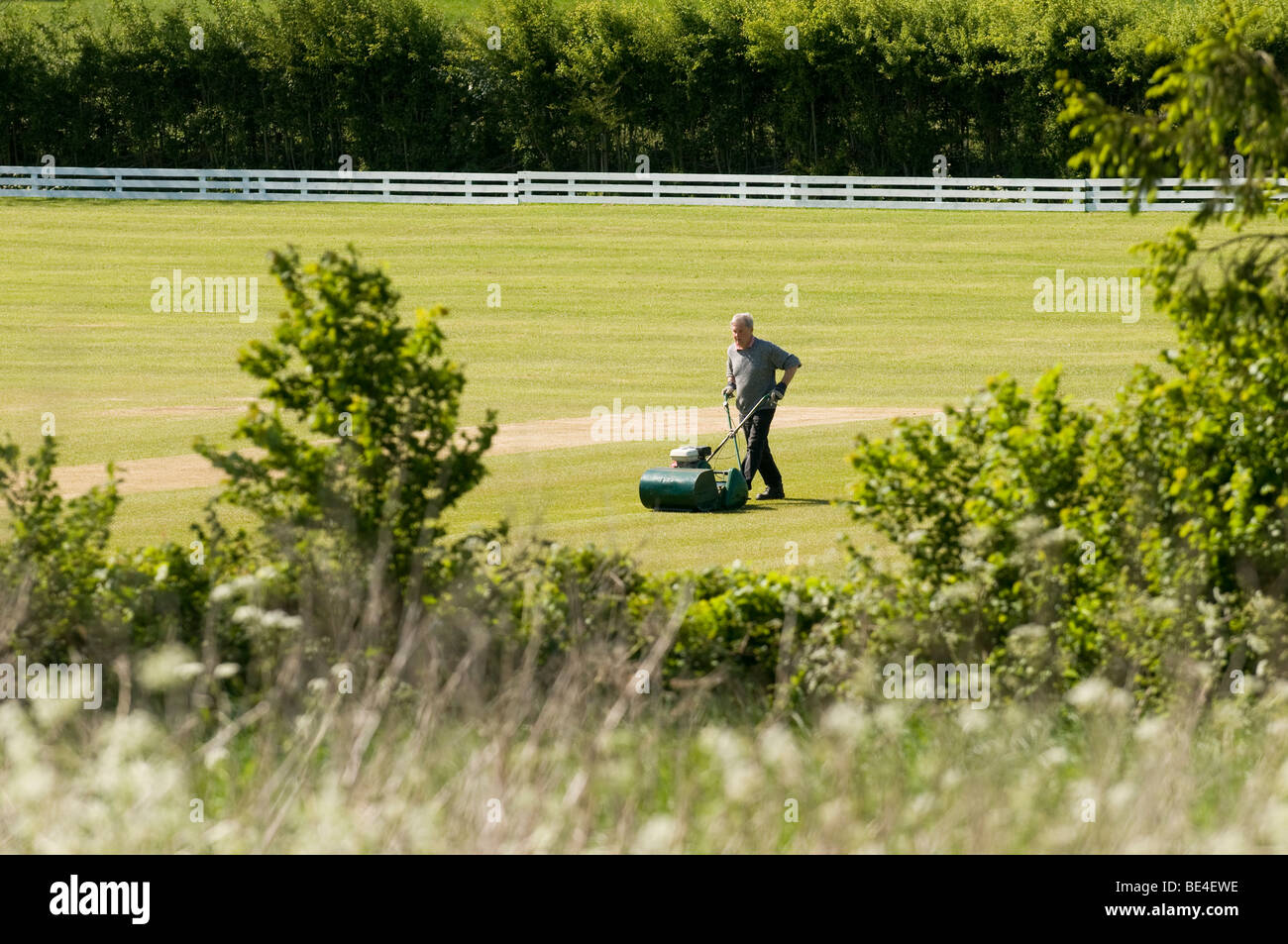 Il campo da cricket in Feckenham Worcestershire essendo falciati dalla groundsman Foto Stock