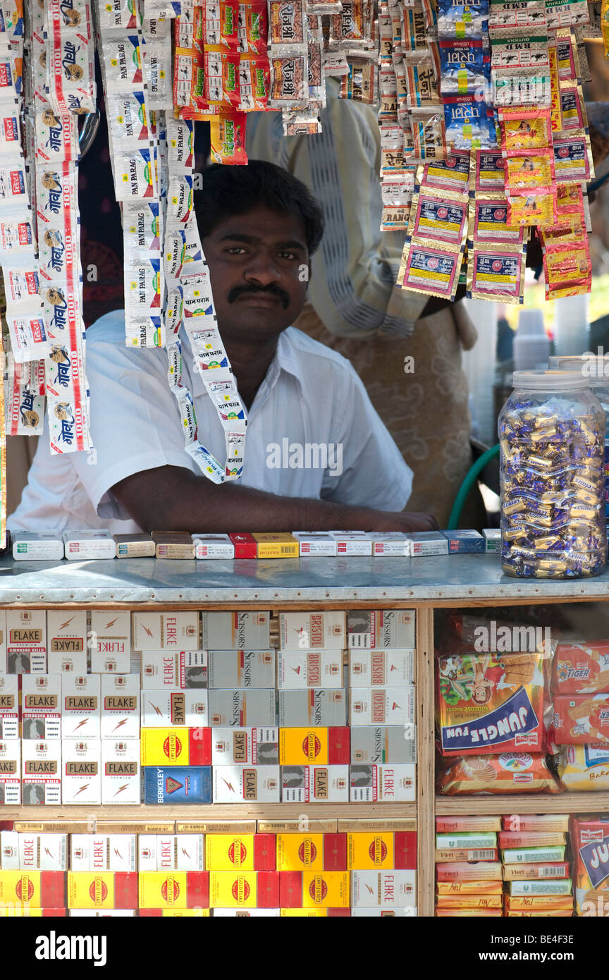 Indian negoziante di dolciumi e di sigarette in una piccola vetrina aperta shop. Andhra Pradesh, India Foto Stock
