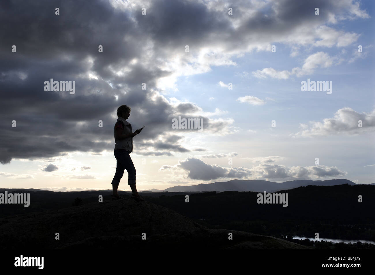 La donna sta al top della Brantfell sopra il Lago Windemere e la città di Bowness nel Lake District in Cumbria Regno Unito Foto Stock